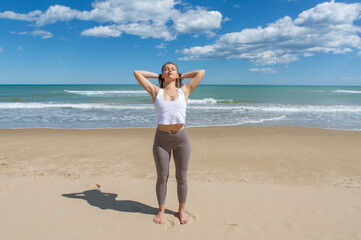 pretty young female athlete stretching on the beach shore
