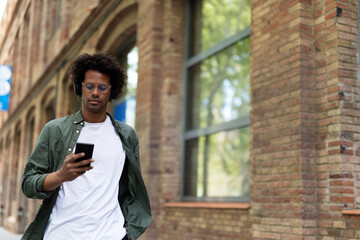 Handsome young man with headphones. Man listening the music while walking through the city.