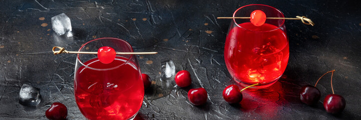 Cocktail with cherry and ice panorama, an aperitif with a garnish on a dark background with berries...