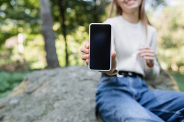 cropped view of happy woman holding smartphone with blank screen.