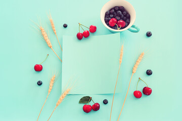 Top view image of colorful assorted mix of berries, blueberry and sweet cherry over pastel blue background