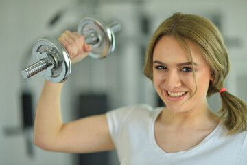 Sporty young woman training with dumbbells  in gym