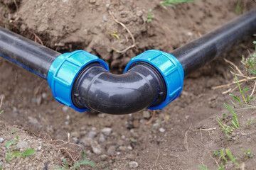 Elbow fitting, pvc pipes at bend in dirt trench outdoors