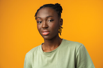 Studio shot of black girl looking suspiciously with skeptical expression in yellow studio