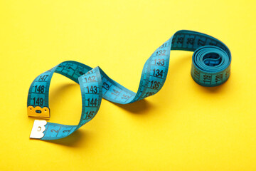 Blue plastic measure tape with metric scale over on color yellow background.