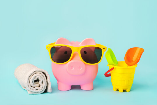 Summer holiday concept.Pink piggy money bank with beach towel,sunglasses and beach bucket