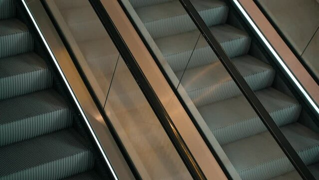 Meditative video of a moving escalator. The steps go up and down. Shiny chrome escalator mechanism. Subway, shopping mall. Public space. No people. Technological equipment of the building. Background