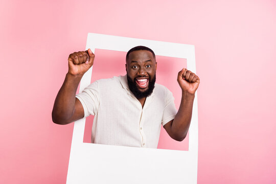 Photo Of Pretty Lucky Young Man Wear White Shirt Rising Fists Standing Inside Photo Frame Isolated Pink Color Background