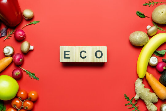 Top view of cubes with eco lettering near ripe fruits and vegetables on red background.