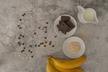 ingredientes para batido de avena, plátano y chocolate sobre fondo de piedra