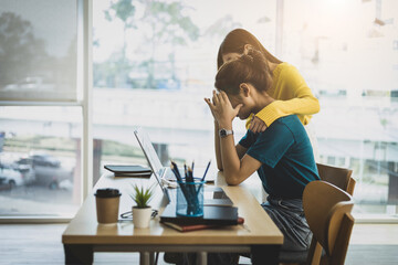 Coworker comforting stressed and discouraged woman in office.