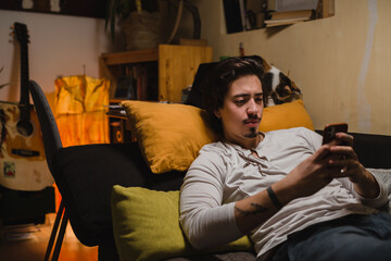Fototapeta premium man using smartphone laying on bed in his room