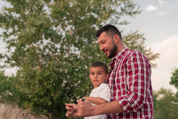 Naklejka na ściany i meble Father and son enjoy riding horses together by the sea. Selective focus 