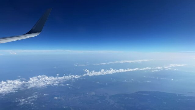 View from the window seat of an aeroplane of the horizon with the cloud formation likely caused by the Jetstream of other aircraft