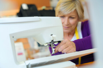 female tailor threading bobbin into sewing machine case