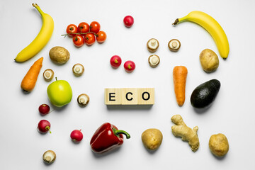 Top view of cubes with eco lettering near organic food on white background.