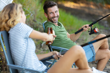 Obraz premium couple of woman and man having a beer while fishing