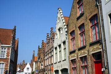 Häuserzeile mit alten Fassaden aus Backstein und Altbauten mit Treppengiebel vor blauem Himmel bei...