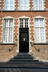 Kunstvolle weiße Sprossenfenster und alte Haustür mit Treppenaufgang in der Fassade aus Backstein...