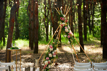 Beautiful bohemian tipi arch decoration on outdoor wedding ceremony venue in pine forest with...