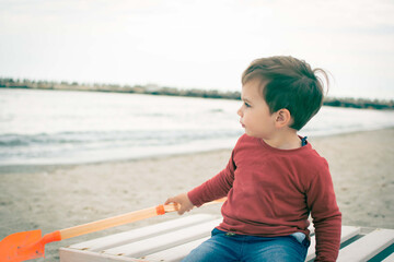 Young boy playing on the beach in sand toddler on empty beach tourism concept pre season family fun...