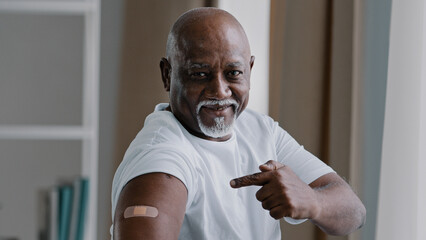 Portrait african american old senior mature man patient shows medical plaster on shoulder...