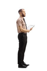 Full length profile shot of a male security officer holding a clipboard
