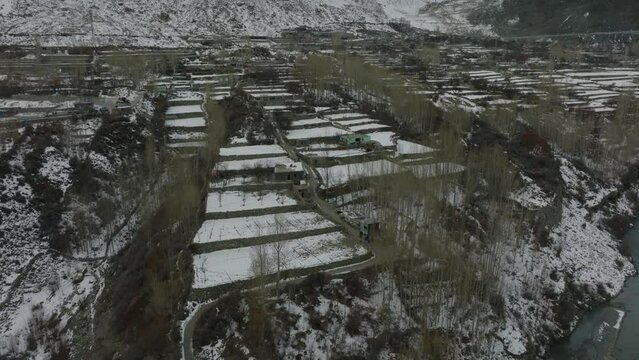 Aerial View Of Snow Covered Terraced Gardens In Rural Town In Hunza Valley Countryside. Pedestal Up, Tilt Down 