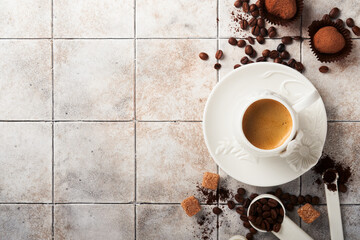 Coffee background. Measuring spoons with ground coffee, beans, cup and sweet chocolate truffles on old tile cracked table background. Food background. Top view with space for your text