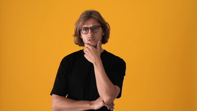 Concentrated blond man looking at the camera and giving positive answer in the yellow studio