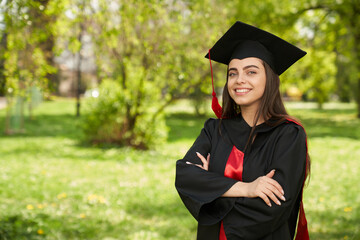 Front view of girl wearing mortarboard and graduate gown smiling. Pretty young female graduating...