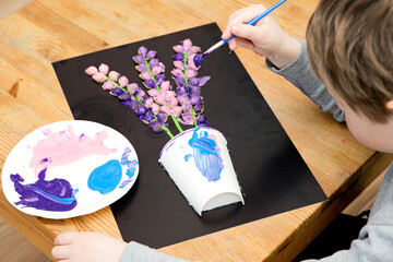 Boy painting with a gouache spring flower. Boy making color paper hyacinths for mommy. Children...