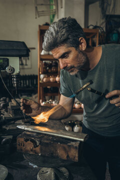 Mature silversmith using gas torch