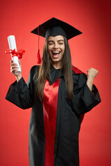 Front view of glad, happy girl graduating from college, university, high school. Pretty young...