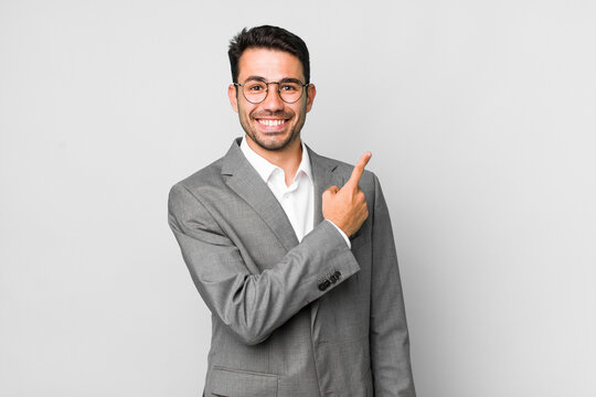 young adult hispanic man smiling cheerfully, feeling happy and pointing to the side. business concept