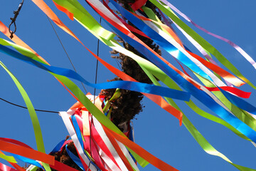 The ribbons of a Maypole blowing in the wind against a clear blue sky  - obrazy, fototapety, plakaty