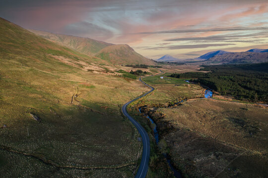 A country side winding road near the Glenlosh Valley in county Galway, Ireland, with mountains in the background