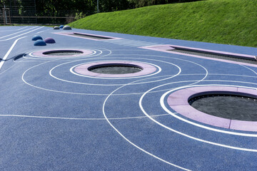 Circular trampolines sunk into the terrain. Modern new playground