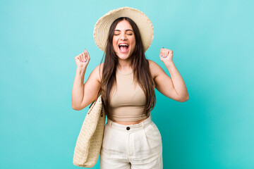 young pretty woman shouting aggressively with an angry expression. summer and hat concept