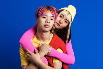 Asian couple with multicolored hair hugging and looking at camera