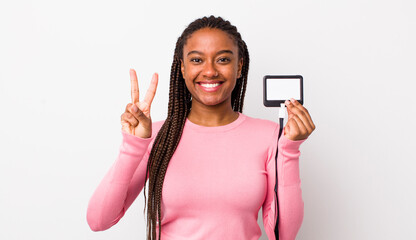 young adult black woman smiling and looking friendly, showing number two. vip pass id concept