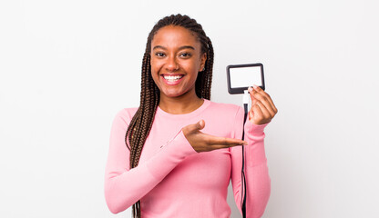 young adult black woman smiling cheerfully, feeling happy and showing a concept. vip pass id concept
