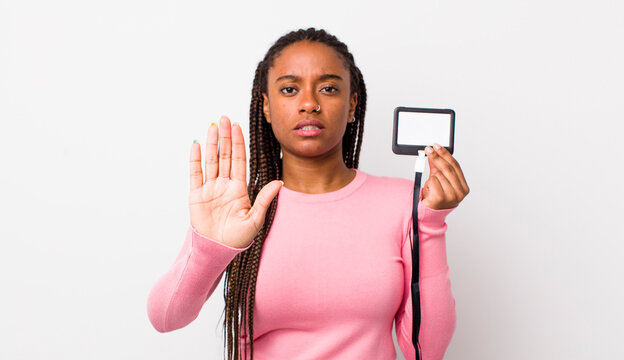 young adult black woman looking serious showing open palm making stop gesture. vip pass id concept