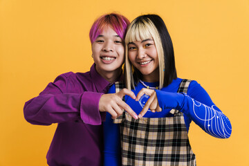Asian couple smiling while showing heart gesture together