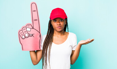 young adult black woman feeling puzzled and confused and doubting. number one hand fan concept