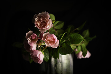 Romantico mazzo di rose recise di colore rosa antico, in vaso trasparente isolato su fondo nero