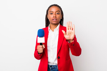 young adult black woman looking serious showing open palm making stop gesture. presenter and...
