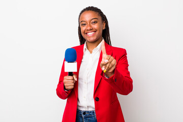 young adult black woman smiling proudly and confidently making number one. presenter and microphone...