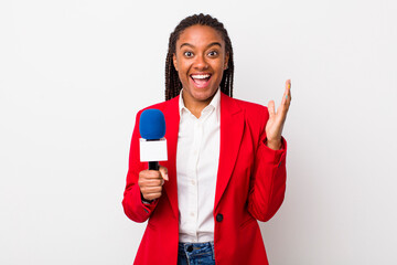 young adult black woman feeling happy and astonished at something unbelievable. presenter and...