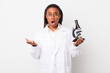 young adult black woman looking surprised and shocked, with jaw dropped holding an object. sciencist with microscope